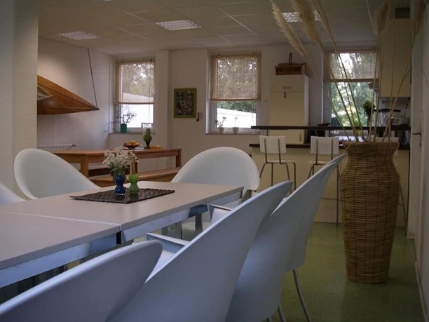 Multifunktionsraum in Kanustation und Seminarhaus Rio Negro Moderner Multifunktionsraum mit weißen Stühlen, Tischgruppen und Küchenecke. Fenster mit Blick ins Grüne.