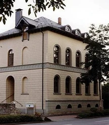 Haus Münsterberg Außenansicht Historisches Gebäude mit hellen Backsteinwänden, rundbogigen Fenstern und einem steilen Dach.