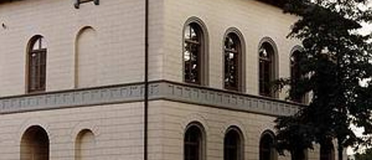 Haus Münsterberg Außenansicht Historisches Gebäude mit hellen Backsteinwänden, rundbogigen Fenstern und einem steilen Dach.