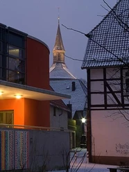 Winterlicher Blick auf den Martiniturm durch moderne und traditionelle Gebäude in der Dämmerung.