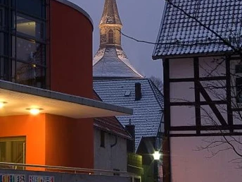 Blick von der Grundschule auf den Martiniturm Winterlicher Blick auf den Martiniturm durch moderne und traditionelle Gebäude in der Dämmerung.