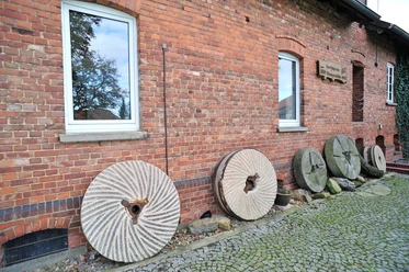 Hartingsche Mühle Hartingsche Mühle: Historische Mühlsteine an einer roten Backsteinfassade, Fenster, Kopfsteinpflaster.