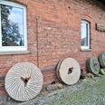 Hartingsche Mühle Hartingsche Mühle: Historische Mühlsteine an einer roten Backsteinfassade, Fenster, Kopfsteinpflaster.