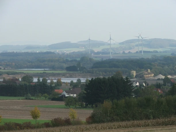 Blick zu den Kiesteichen Blick auf Kiesteiche mit umliegenden Feldern, Windrädern und sanften Hügeln im Hintergrund.