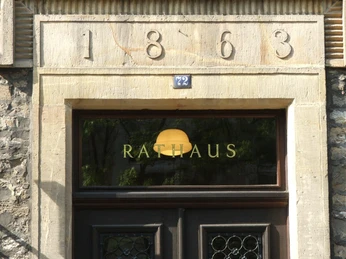 Rathaus Lage Eingang eines historischen Rathauses mit Baujahr 1863 über der Tür und Glastür mit Rathaus-Schriftzug.