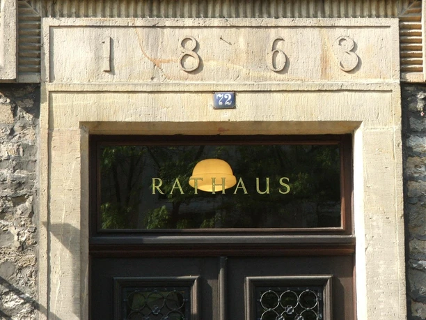Rathaus Lage Eingang eines historischen Rathauses mit Baujahr 1863 über der Tür und Glastür mit Rathaus-Schriftzug.