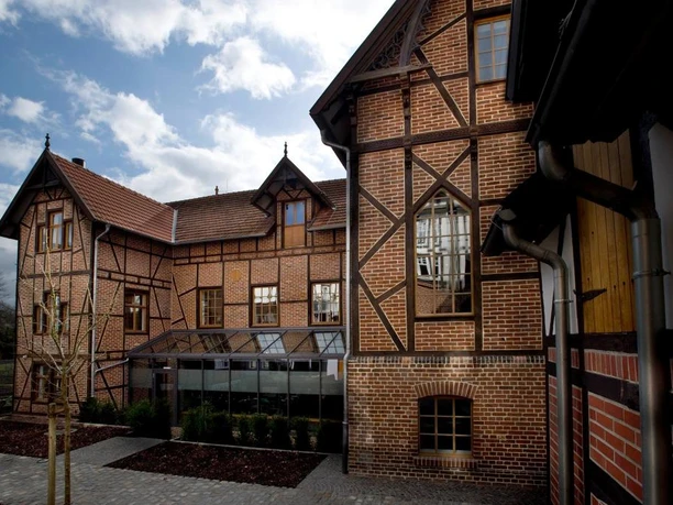 Eine historische Fachwerkfassade mit roten Ziegeln und Giebeln unter einem bewölkten Himmel.