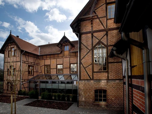 Museum "Wiedenbrücker Schule" Eine historische Fachwerkfassade mit roten Ziegeln und Giebeln unter einem bewölkten Himmel.