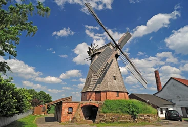 Büschingsmühle Historische Windmühle aus Backstein und Holz in ländlicher Umgebung mit malerischem Himmel im Hintergrund.