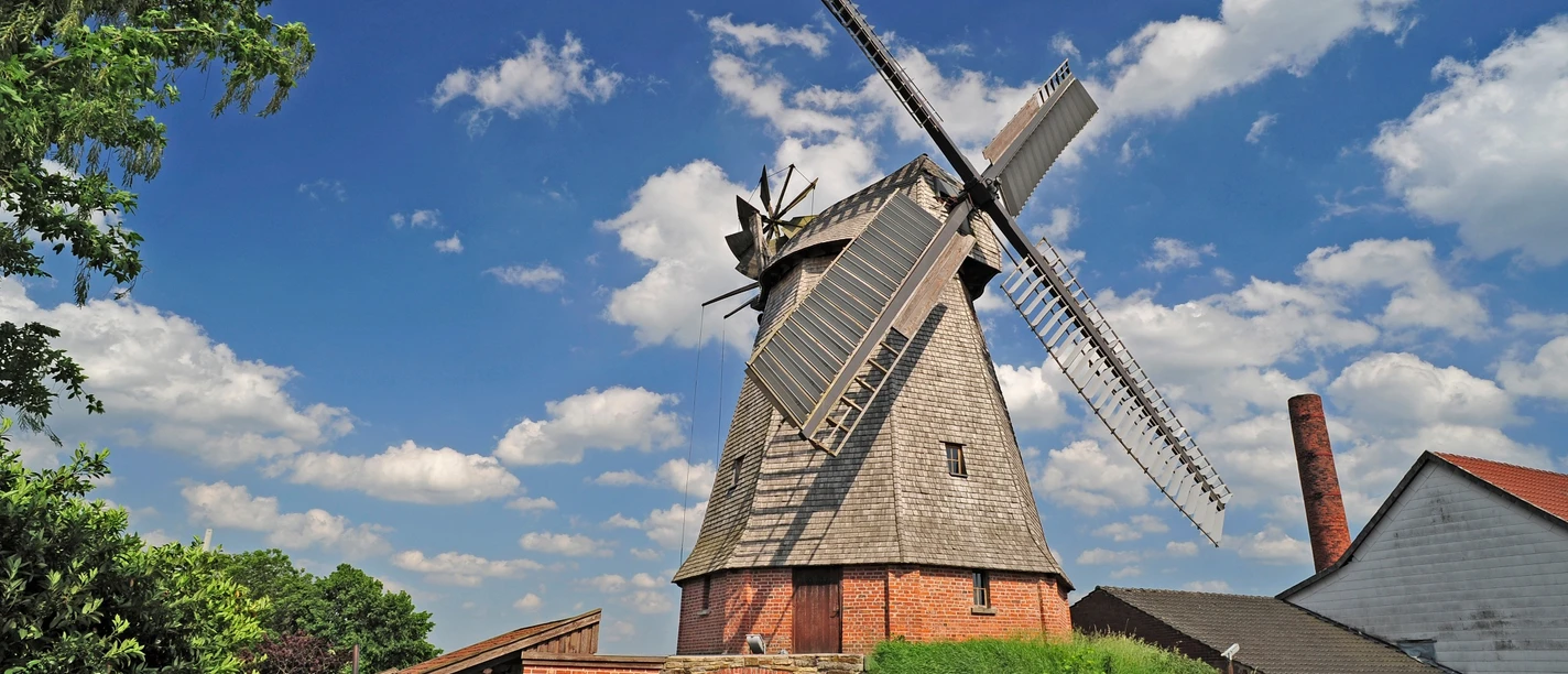 Büschingsmühle Historische Windmühle aus Backstein und Holz in ländlicher Umgebung mit malerischem Himmel im Hintergrund.
