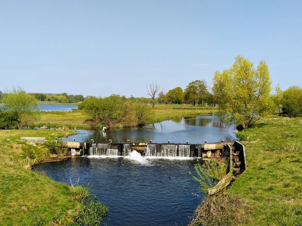 Steinhorster Becken Weite Landschaft mit Wasserbecken, Wehren und Bäumen unter blauem Himmel. Naturschutzgebiet.