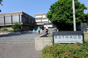 Rathaus Versmold Familie geht vor modernem Backsteingebäude zum Haupteingang des Rathauses mit grüner Umgebung.