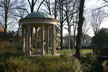 Kriegerdenkmal Pavillon im Park mit Säulen und Kuppeldach, umgeben von Bäumen und Landschaft im Winter.