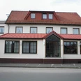 Hörster Krug Traditionelles Gasthaus mit rotem Ziegeldach, weißen Wänden und großen Fenstern an einer Straße.