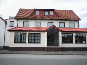 Hörster Krug Traditionelles Gasthaus mit rotem Ziegeldach, weißen Wänden und großen Fenstern an einer Straße.