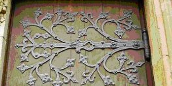 CK Schmiedekunst Massive Holztür mit kunstvollen, verzweigten Schmiedeeisen-Verzierungen im floralen Stil.