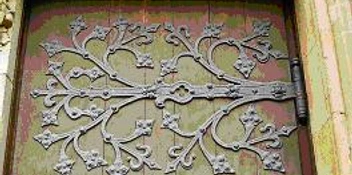 CK Schmiedekunst Massive Holztür mit kunstvollen, verzweigten Schmiedeeisen-Verzierungen im floralen Stil.