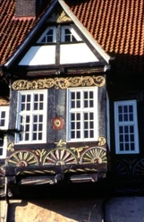 Fachwerkdetail Blomberg Fachwerkfassade in Blomberg mit kunstvollen Verzierungen und hellen Fenstern vor rotem Ziegeldach.