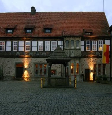 Burghof Historischer Burghof mit altem Brunnen, umgeben von Fachwerkgebäuden, in abendlicher Beleuchtung.