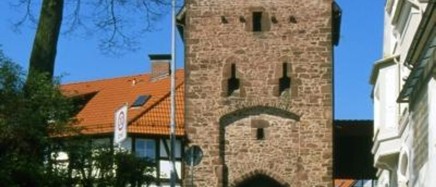 Historisches Stadttor aus rotem Sandstein mit Rundbogen in Blomberg, umgeben von Fachwerkhäusern.