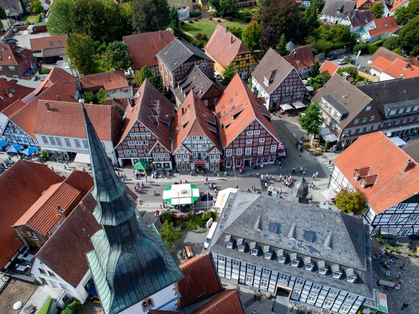 Luftaufnahme von historischen Fachwerkhäusern einer charmanten Altstadt mit Menschen auf der Straße.