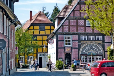 Müntestraße Fachwerkhäuser mit bunten Fassaden an einer gepflasterten Straße; Passanten und Fahrräder davor.