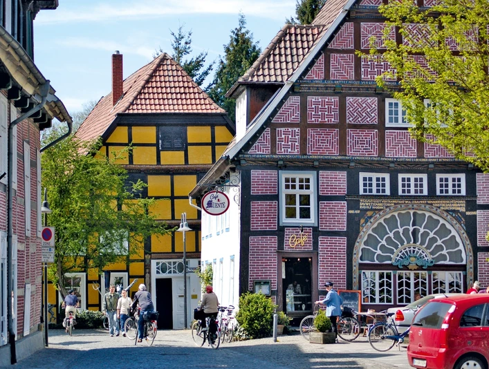 Müntestraße Fachwerkhäuser mit bunten Fassaden an einer gepflasterten Straße; Passanten und Fahrräder davor.