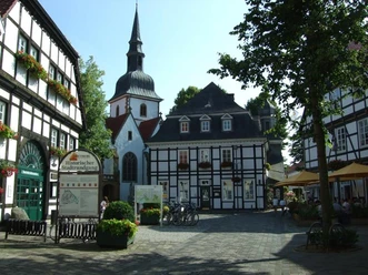 Bolzenmarkt im Historischen Stadtkern Fachwerkhäuser und Kirche in einer historischen Altstadt mit sonnigem Platz und Café-Tischen.