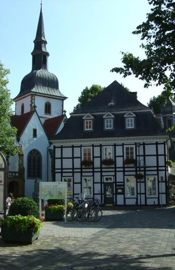 Bolzenmarkt im Historischen Stadtkern Fachwerkhäuser und Kirche in einer historischen Altstadt mit sonnigem Platz und Café-Tischen.