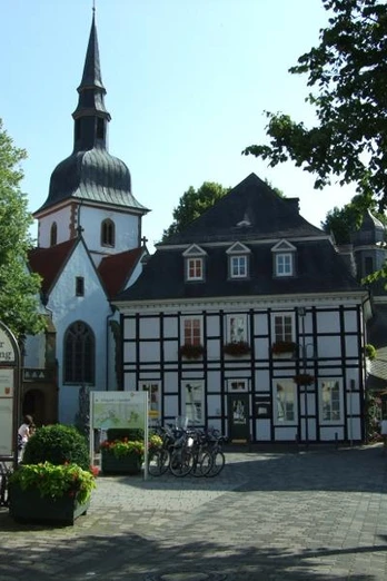 Bolzenmarkt im Historischen Stadtkern Fachwerkhäuser und Kirche in einer historischen Altstadt mit sonnigem Platz und Café-Tischen.