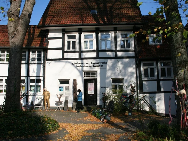 Fachwerkhaus mit "Kindheits- und Jugendwerke bedeutender Künstler" in herbstlicher Parkanlage.