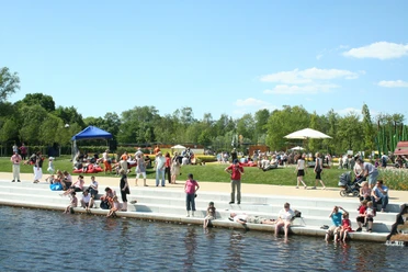 Entspannung am Untersee Menschen entspannen sich an einem sonnigen Tag am Ufer eines Flusses in einem belebten Park.