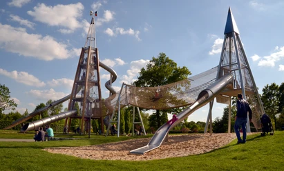 Das Wahrzeichen im Parkteil Nord - der Rutschenturm Moderne Spielplatzstruktur aus Metall mit Röhrenrutschen und Kletterelementen in einem Park.