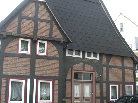 Fachwerkhaus Rhienstraße 32 Fachwerkhaus mit auffälligem steilen Schieferdach, schmalen Fenstern und bemalten Backsteinmustern.