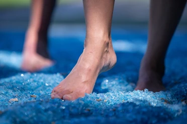 Kneipp-Pfad im Erlebnis- & Gesundheitspark Bad Salzuflen Barfuß gehen auf blauen Glasscherben im Kneipp-Pfad, fördert Balance und Fußreflexzonenmassage.