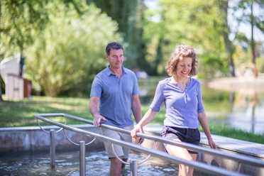 Kneipp-Pfad im Erlebnis- & Gesundheitspark Bad Salzuflen Ein Paar genießt den Kneipp-Pfad und taucht barfuß in das erfrischende Wasserbecken ein.
