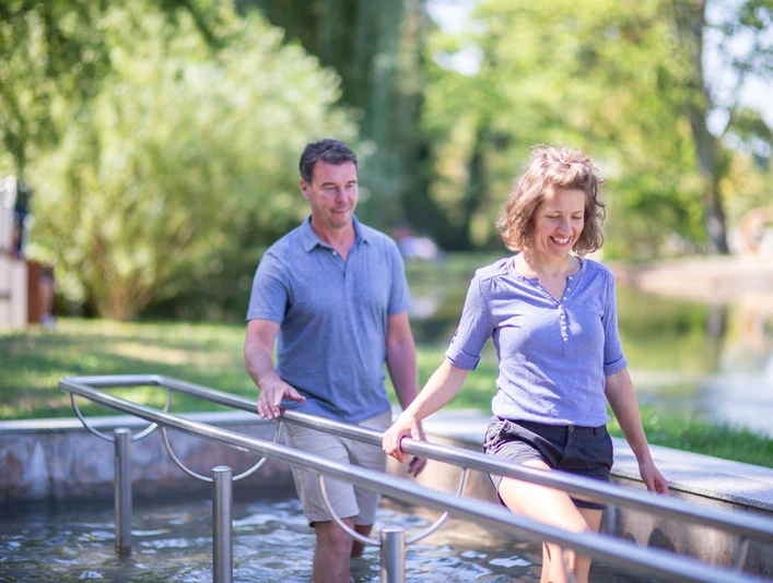Kneipp-Pfad im Erlebnis- & Gesundheitspark Bad Salzuflen Ein Paar genießt den Kneipp-Pfad und taucht barfuß in das erfrischende Wasserbecken ein.