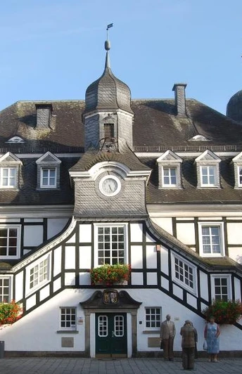 Historisches Rathaus Historisches Fachwerk-Rathaus mit markantem Turm und blühenden Blumenkästen, umgeben von Bäumen.