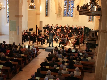 Konzert in der Petri Kirche Kirchenkonzert mit Orchester und Publikum, gotische Architektur, Buntglasfenster im Hintergrund.