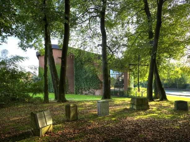 Ev. Versöhnungskirche 1 Evangelische Kirche aus rotem Ziegelstein, teils mit Efeu bewachsen, von hohen Bäumen umgeben.
