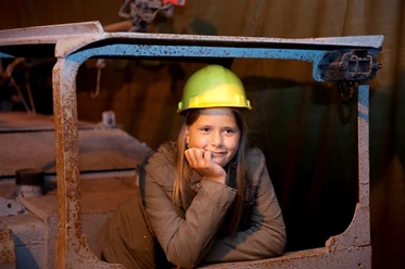 Besucherbergwerk Kleinenbremen Mädchen mit Helm in Waggon eines Besucherbergwerks, lächelnd nachdenklich in der Kohlemine.