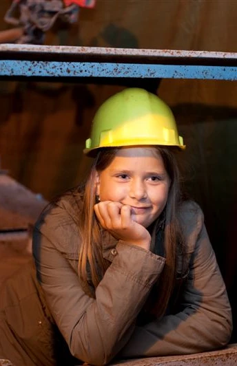 Besucherbergwerk Kleinenbremen Mädchen mit Helm in Waggon eines Besucherbergwerks, lächelnd nachdenklich in der Kohlemine.