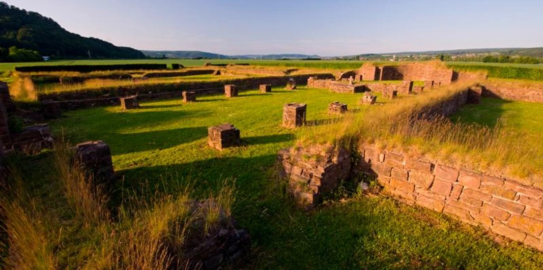 Überreste einer Klosterruine in Höxter, umgeben von Wiesen und sanften Hügeln bei Sonnenuntergang.