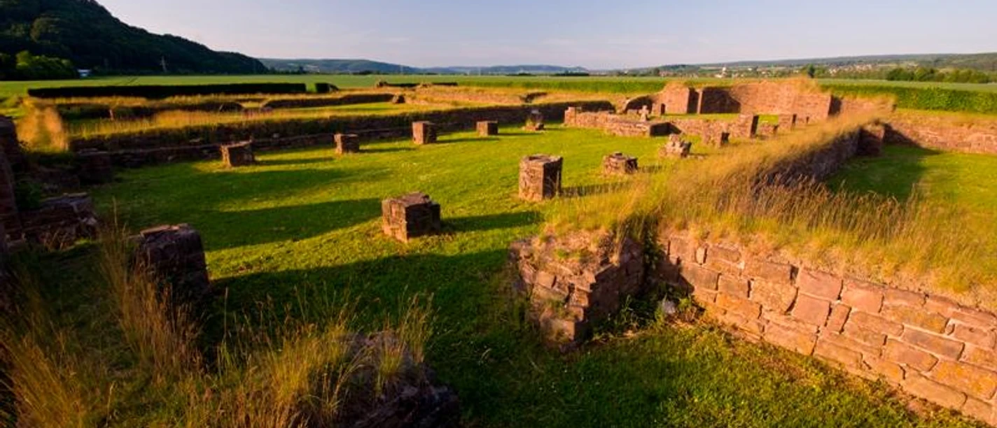 Überreste einer Klosterruine in Höxter, umgeben von Wiesen und sanften Hügeln bei Sonnenuntergang.