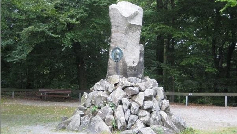 Bismarckstein Steinerne Gedenksäule im Wald zu Ehren von Otto von Bismarck, umgeben von Bäumen und Kiesweg.