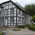Haus des Gastes Fachwerkhaus mit weißen Wänden und dunklen Holzbalken, umgeben von gepflegten Grünanlagen.