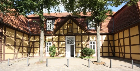Altes Progymnasium und Standesamt Historisches Fachwerkgebäude mit gelber Fassade und roten Dachziegeln, flankiert von Bäumen.