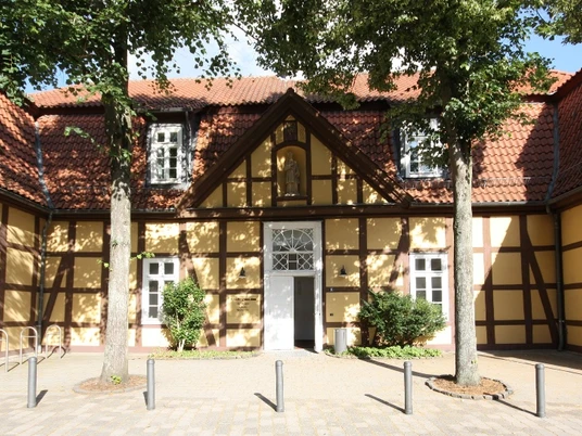 Altes Progymnasium und Standesamt Historisches Fachwerkgebäude mit gelber Fassade und roten Dachziegeln, flankiert von Bäumen.