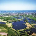 Luftaufnahme von zahlreichen blauen Teichen in einer ländlichen, grünen Landschaft mit Kleinstadt im Hintergrund.