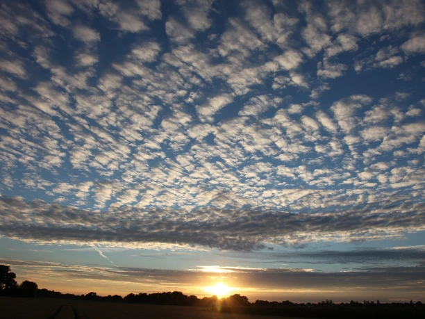 Abendhimmel Versmolder Bruch Sonnenuntergang über einem flachen Landschaftshorizont mit dramatischen Wolkenformationen am Himmel.